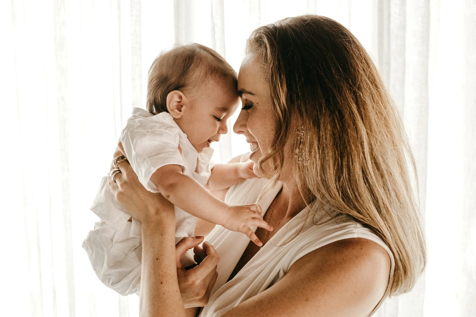 A smiling mother lifting her baby close to her face