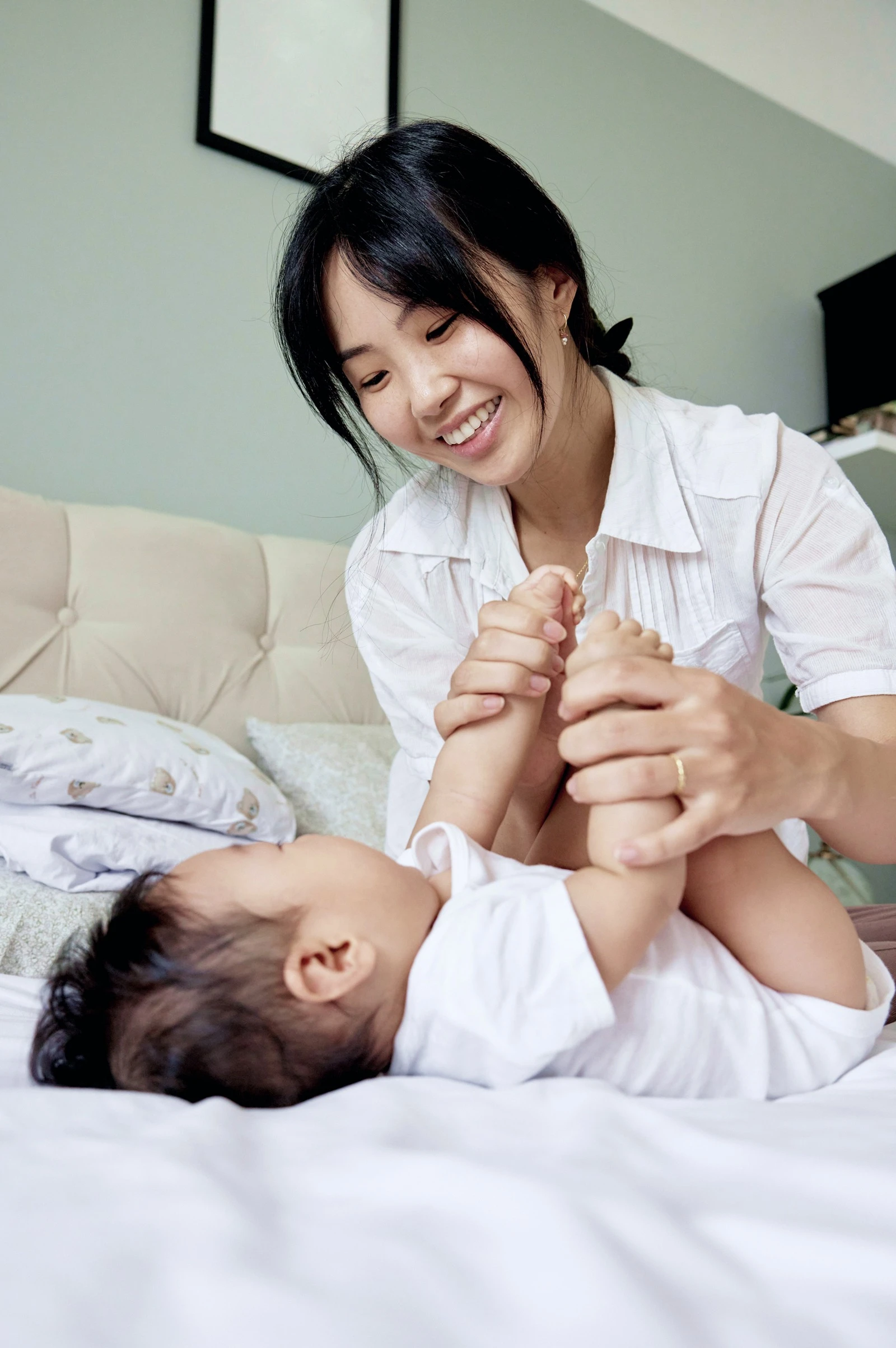 A smiling mother playing with her baby lying on the bed